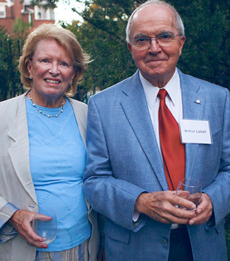 Sonia and Arthur Labatt are shown smiling outdoors, in front of greenery, while standing close together in business formal wear.