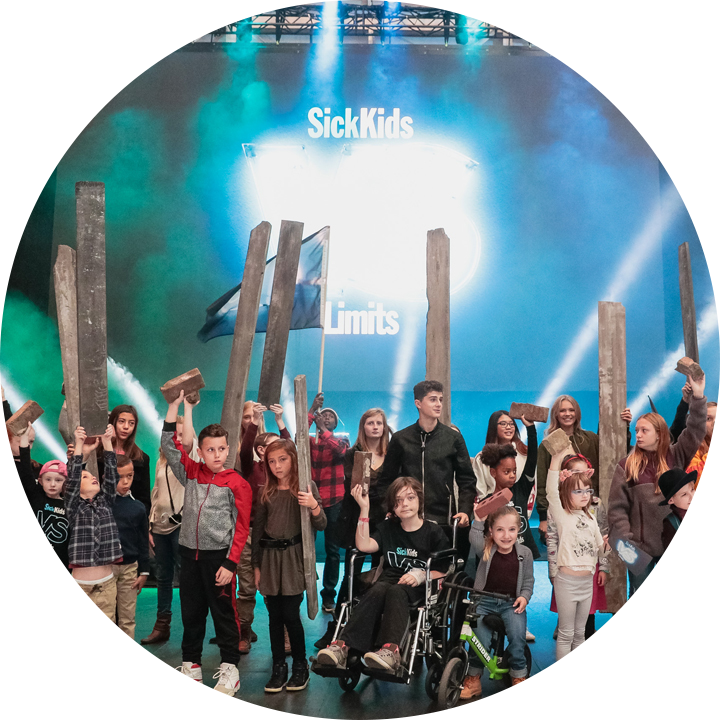 A group of SickKids patients, holding bricks and wooden planks in front of the SickKids VS Limits logo.