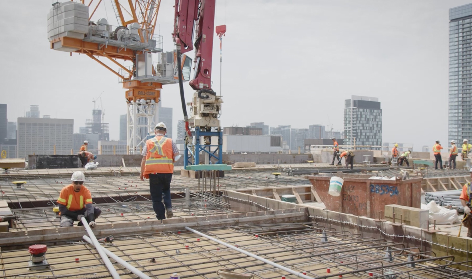 Construction workers are shown building the Patient Support Centre, with a look from the top of the building and distant towers in the background.