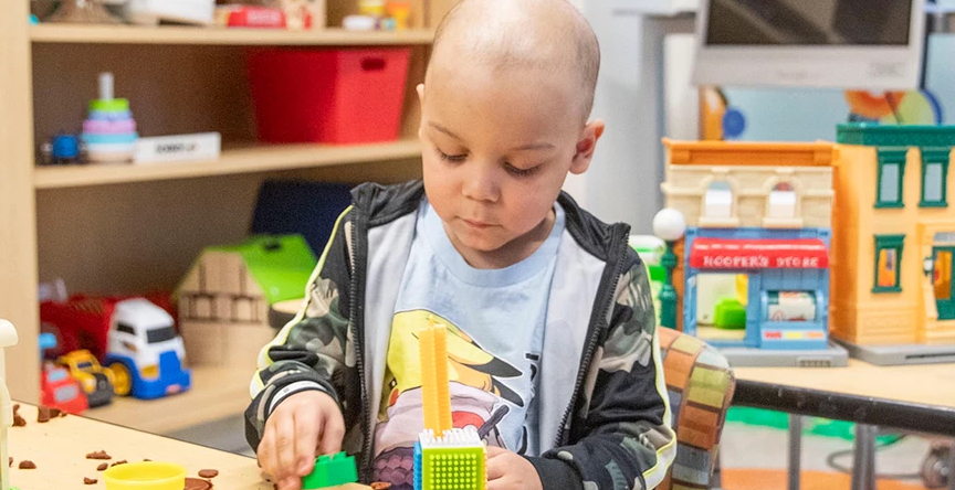 A young boy plays with clay in a waiting room at SickKids.
