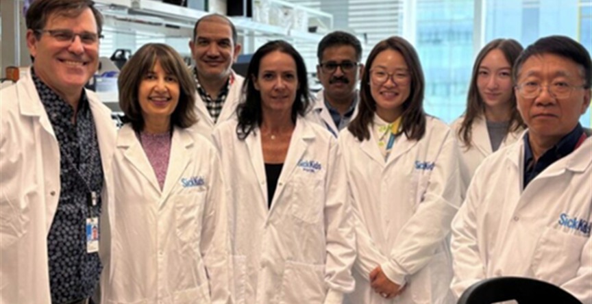 Seema Mital stands in a research lab with members of the lab team in research coats