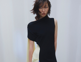 A model posing in a black dress, accented with white and blue fabric