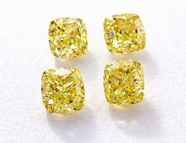 Two sets of yellow diamond earrings on a white backdrop 
