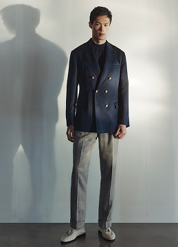 A model wears a black jacket and grey pants from Holt Renfrew.